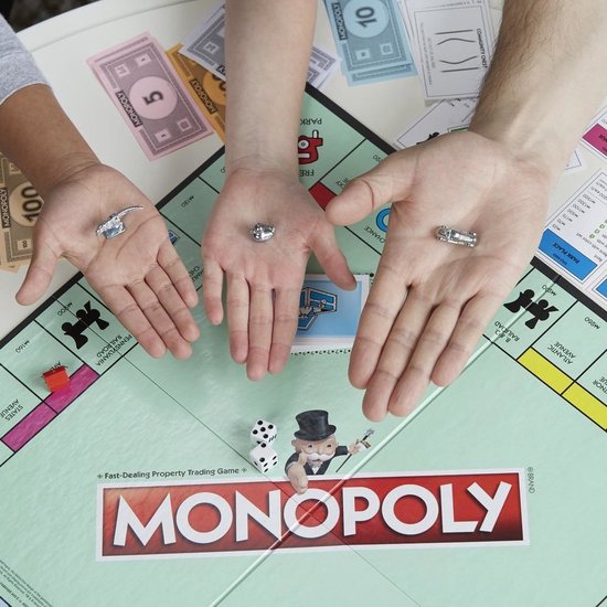 Drie handen tonen Monopoly speelstukken: ring, schaats en auto