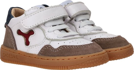 Close-up van witte leren sneakers met bruine suède, klittenband en rode detail.