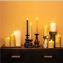 Een collectie van diverse LED kaarsen in verschillende maten en kleuren, waaronder goud en wit, op een dressoir.