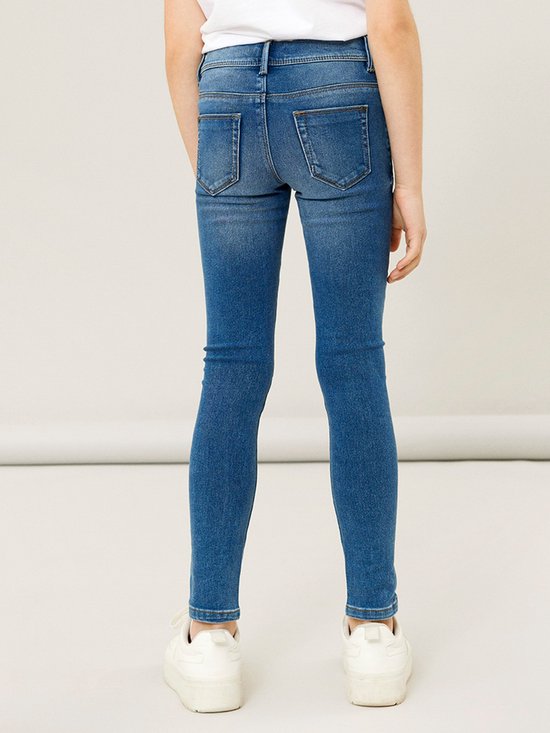 Meisje in een blauwe skinny spijkerbroek, van achteren gezien.