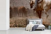 Behang - Fotobehang Een cowboy op zijn paard die het vee bewaakt - Breedte 330 cm x hoogte 220 cm