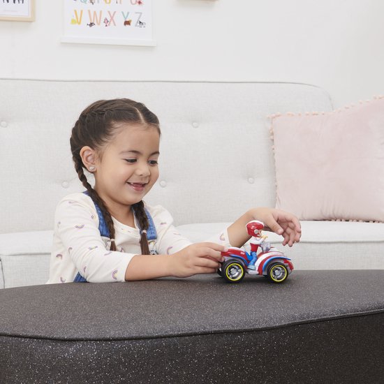 Een meisje speelt met de rode, witte en blauwe PAW Patrol ATV van Ryder met een jongen erop.