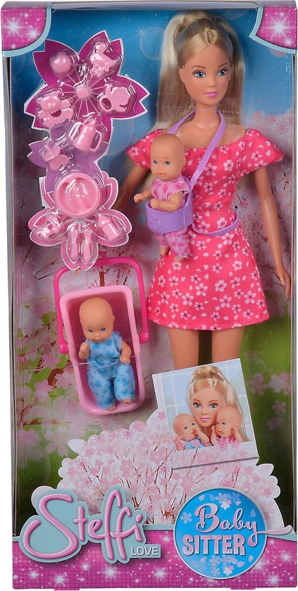 Doos met Steffi Love pop als babysitter. Ze draagt een roze jurk en een babydrager met baby. Een wiegje met baby staat naast haar.
