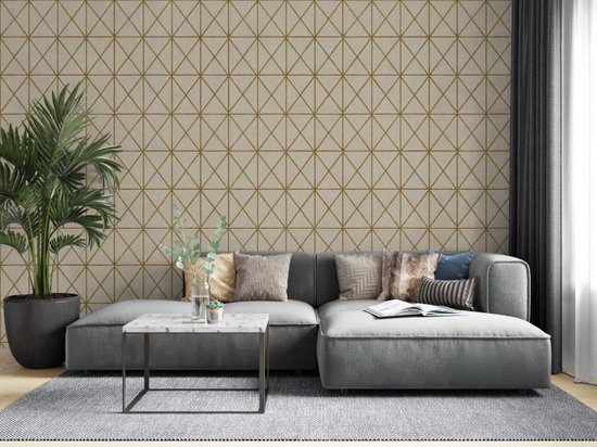 Moderne woonkamer met een grijze hoekbank, kussens, een bijzettafel, plant en beige behang met goudkleurig rasterpatroon.