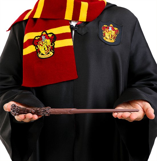 Persoon in een zwarte tovenaarjas met Gryffindor-sjaal en -wapen, die een bruine toverstaf vasthoudt.