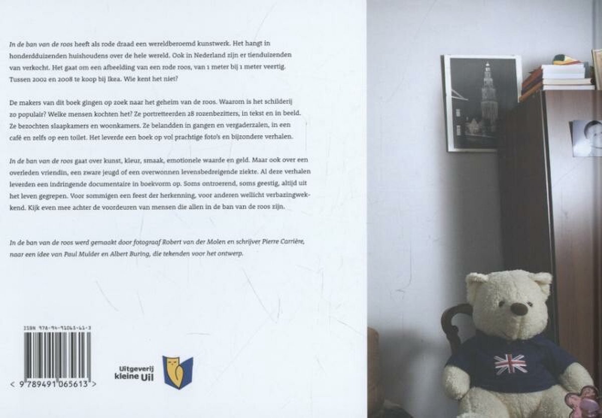 Een teddybeer met een shirt met de Britse vlag zit op een bank, naast boeken en een foto.