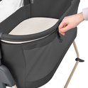 Main ouvrant la fermeture éclair d'un co-sleeper gris foncé avec pieds beiges et matelas.