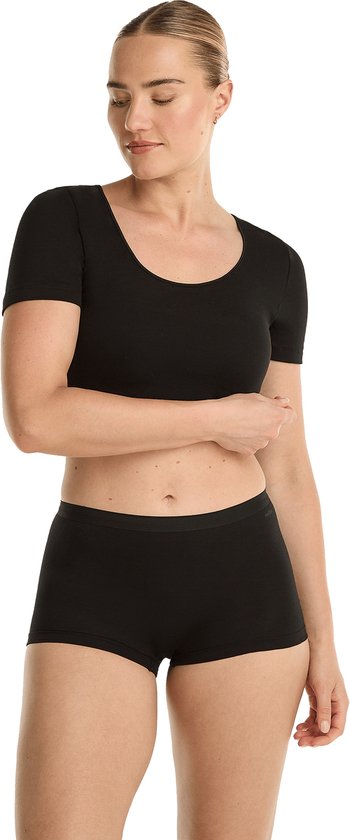 Model met een zwarte crop top met korte mouwen en zwarte shorts.