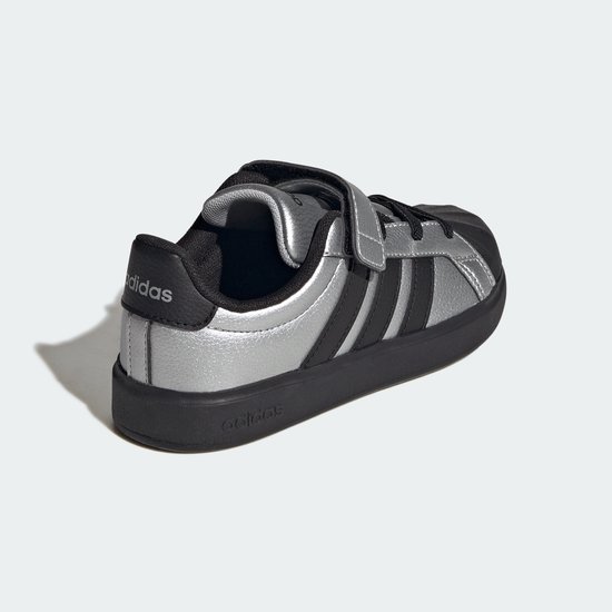 Zilverkleurige sneaker met zwarte accenten en klittenbandsluiting. Adidas logo op de hiel.