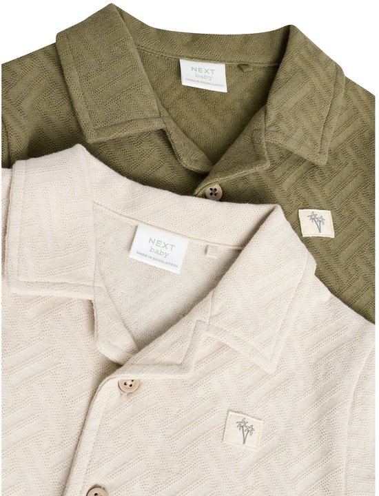 Close-up van de kragen van beige en groene babyrompertjes met visgraatpatroon.