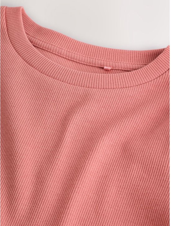 Close-up van een oudroze, langarmige top van geribbelde stof.