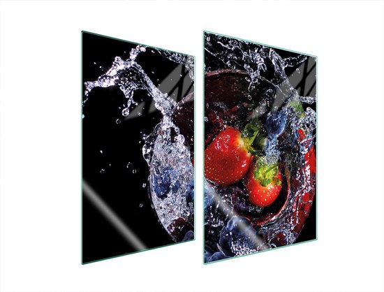 Glasplaat met rode aardbeien en blauwe bessen in opspattend water op een zwarte achtergrond.