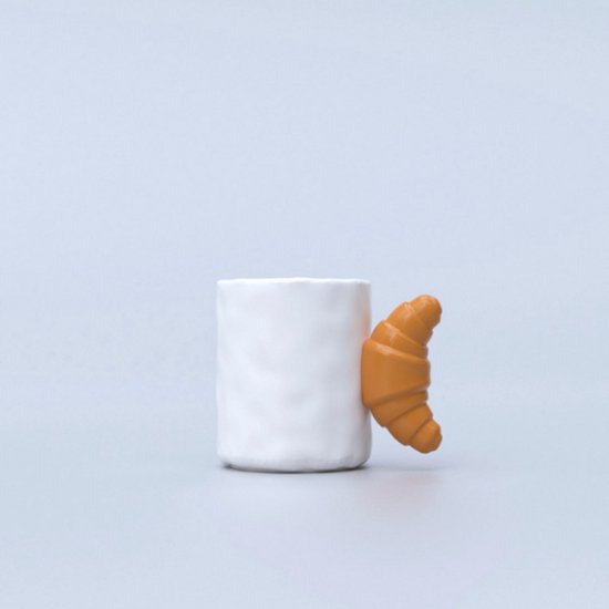 Witte mok met een bruin-oranje croissant als oor.