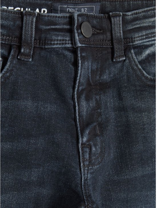 Detail van de tailleband van een donkerblauwe spijkerbroek, met knoop en ritssluiting.