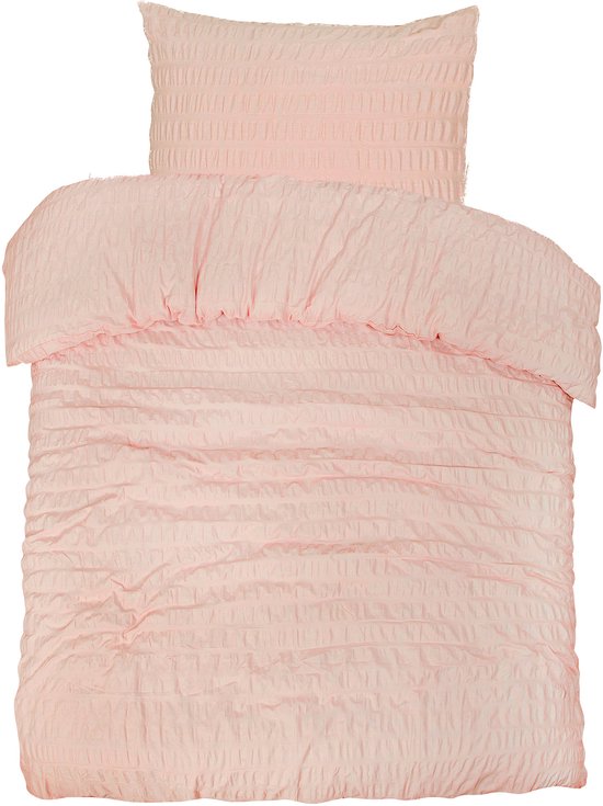 Couette et taie d'oreiller rose pêche texturées pliées.