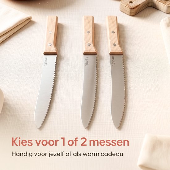 Drie Broba broodmessen met gekartelde bladen en houten handvatten, naast elkaar op een lichte, stoffen ondergrond. "Kies voor 1 of 2 messen"