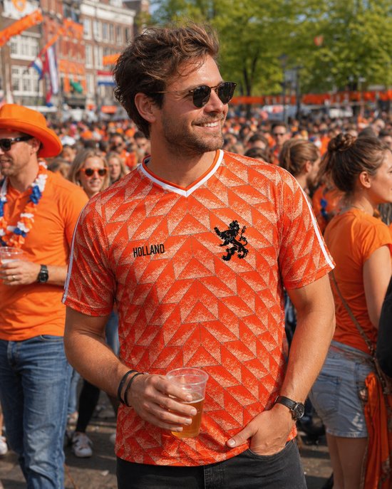 Homme portant des lunettes de soleil et un maillot de football orange 'HOLLAND' lors d'un événement bondé.