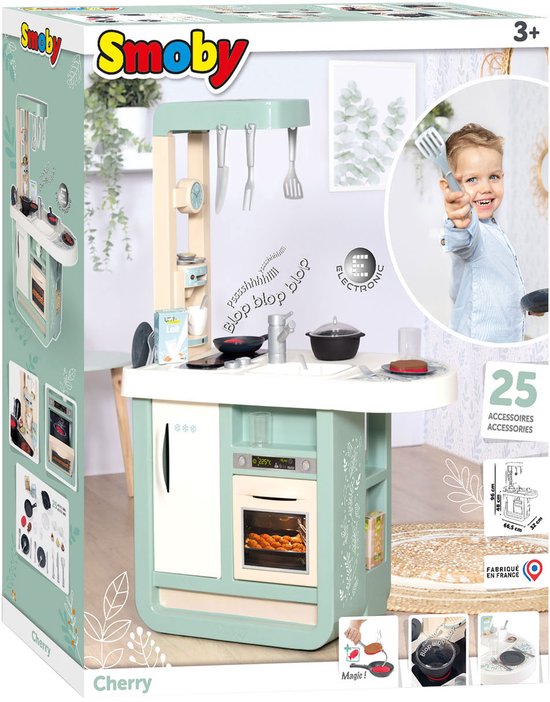 Doos van de Smoby Cherry speelkeuken met een jongen die een vork omhoog houdt en informatie over 25 accessoires.