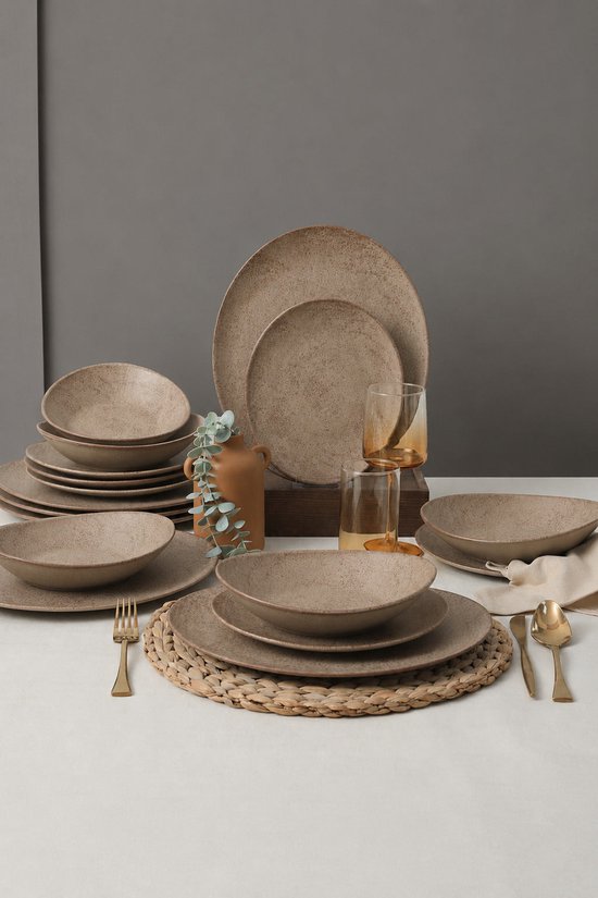 Een gedekte tafel met bruinbeige aardewerken servies, glazen, bestek en decoratie.