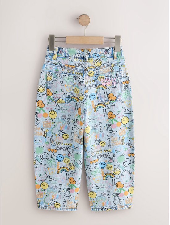 Lichtblauwe, wijde jeans met all-over print van Smiley World-figuren, hangend aan een rek. Met 'Smiley World' logo.