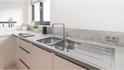 Keukenkraan in een lichte keuken met dubbele spoelbak en witte kasten.