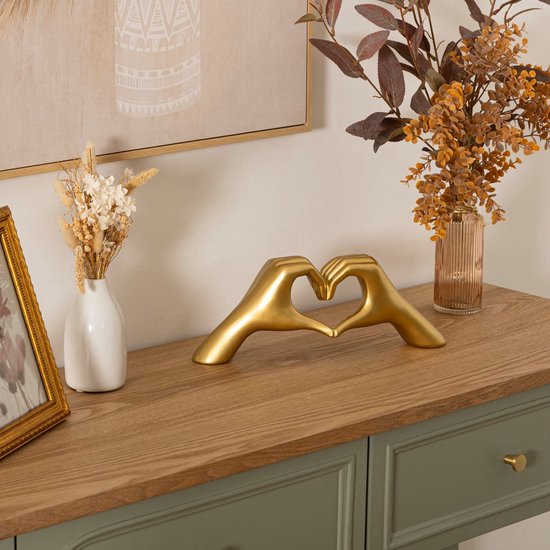 Gouden decoratie van handen die een hart vormen, op een dressoir.