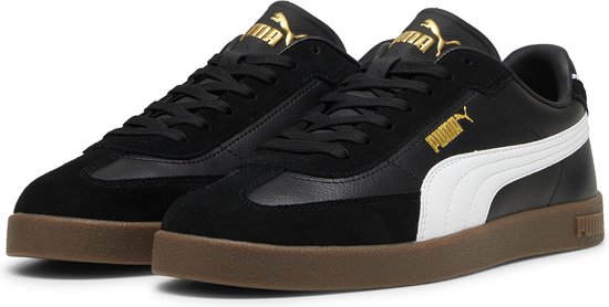 Paar zwarte sneakers met witte Puma-streep, gouden logo en bruine zool.