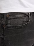 Detail van de voorkant van een zwarte jeans met een zakje en klinknagels.