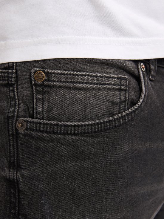 Detail van de voorkant van een zwarte jeans met een zakje en klinknagels.