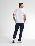 Man met rug naar voren, draagt een witte t-shirt en donkerblauwe cargobroek.