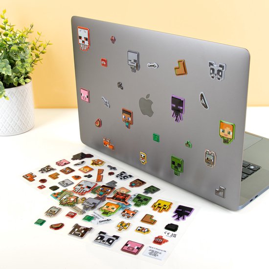 Un ordinateur portable orné de nombreux autocollants Minecraft, tels que Steve, un panda et un Creeper. Une feuille d'autocollants est posée devant.