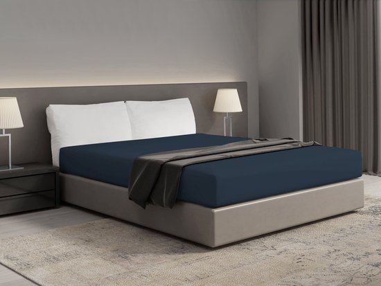 Drap-housse bleu foncé sur un lit double avec un jeté gris foncé.