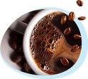 Een kopje dampende koffie met melkschuim en rondvliegende koffiebonen.
