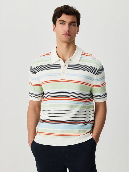 Man met donker haar draagt een wit poloshirt met horizontale strepen in groen, rood, blauw en zwart.