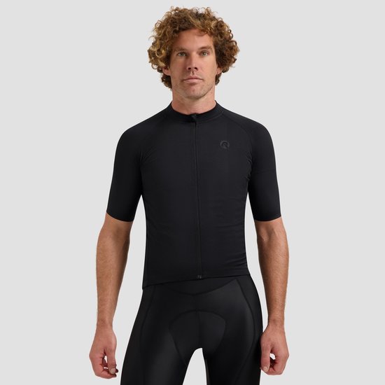 Man met krullend haar in een zwarte wielertrui met korte mouwen en zwarte fietsbroek.