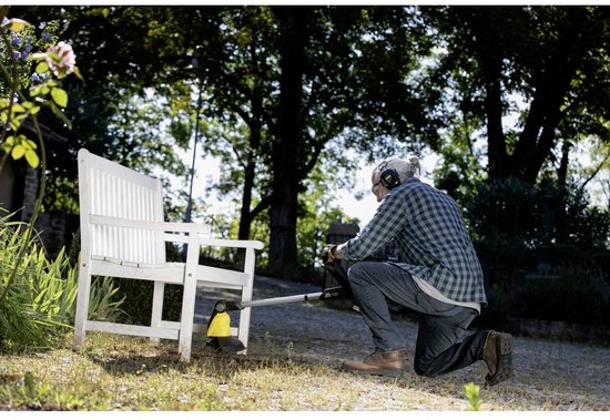 Man op knieën gebruikt de gele voegenborstel bij een witte tuinbank.