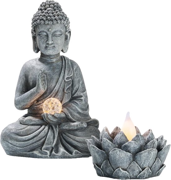 Grijze Boeddha zittend met verlichte bal, naast een grijze lotusbloem kandelaar.