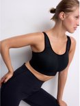 Zijaanzicht van een model in zwarte sportbeha en legging, benadrukt de pasvorm.
