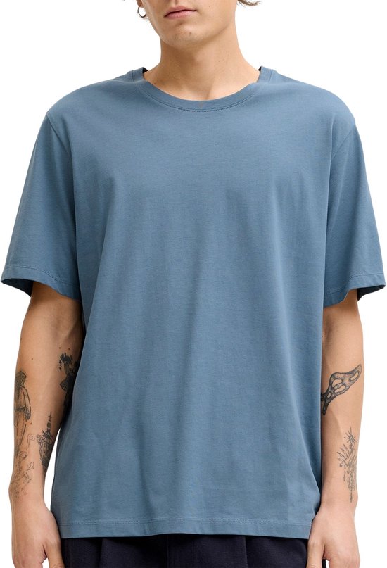 Homme portant un t-shirt bleu uni à manches courtes.