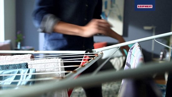 Gros plan d'un étendard pliable blanc et bleu avec des lignes de séchage blanches et des accents rouges, avec du linge dessus.