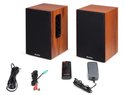 Twee houten boekenplank speakers met zwarte fronten, samen met kabels, afstandsbediening en adapter.