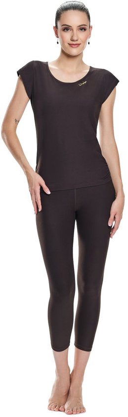 Model draagt een donkerbruin shirt met korte mouwen en een bijpassende driekwart legging. Een klein gouden logo is op de borst geborduurd.