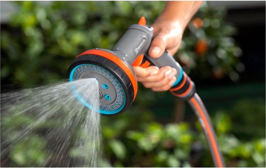 Grijze GARDENA spuit met oranje accenten sproeit water.