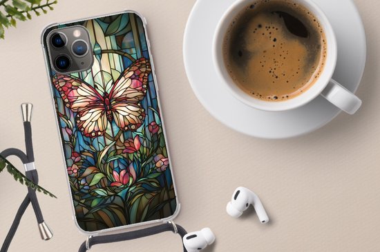 Doorzichtig telefoonhoesje met roze en bruine vlinder, bloemen en bladeren in glas-in-loodstijl, met zwart koord, naast koffie.