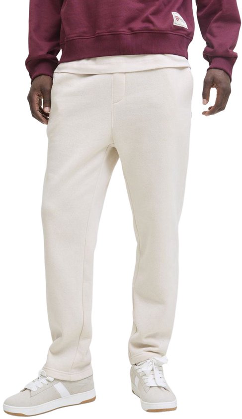 Man met crème joggingbroek en sneakers met strepen.