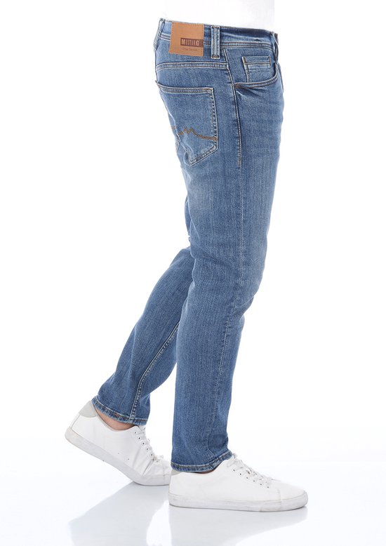 Zijaanzicht van een model met blauwe Mustang jeans, witte sneakers en een leren Mustang True Denim label.