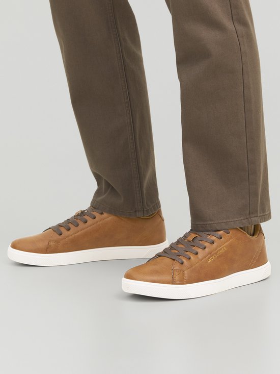 Voet van een man met bruine leren Jack & Jones sneakers en bruine broek.