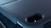 Gedetailleerde close-up van de donkergrijze achterkant van een tablet, met de cameralens en de zijkant van een toetsenbord.