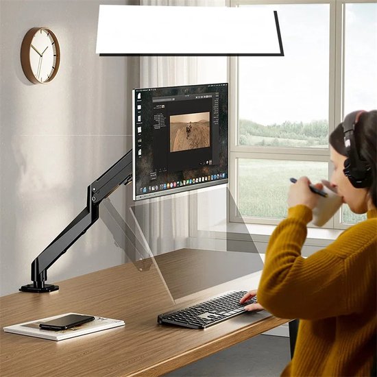 Zwarte, verstelbare monitorarm op een bureau, met een monitor waarop een foto wordt getoond. Een persoon zit aan het bureau.