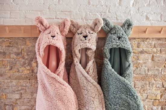 Roze, beige en groene baby wikkeldekens met dierenoren hangen aan haken.
